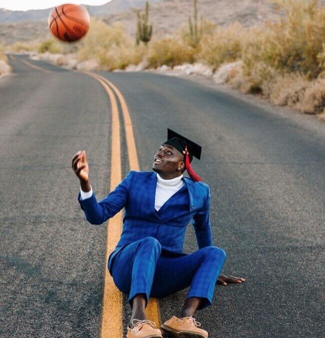 Glendale Community College graduate, Jerry Iliya, throws basketball in a desert street for a senior photo