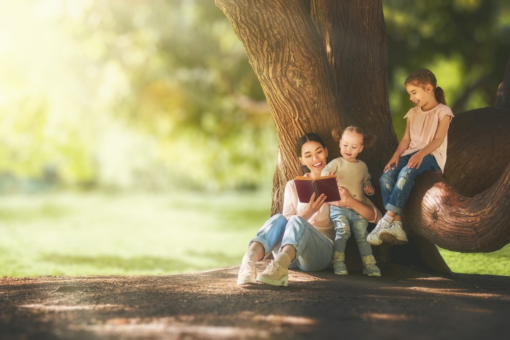 A foster family having a fun day under a shady tree in the park on a sunny day